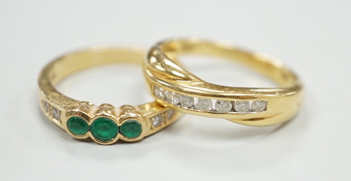 A modern 18ct gold and cannel set seven stone diamond crossover ring, size O and a similar 18k, three stone emerald and four stone diamond chip set ring, size N/O, gross weight 7.8 grams.